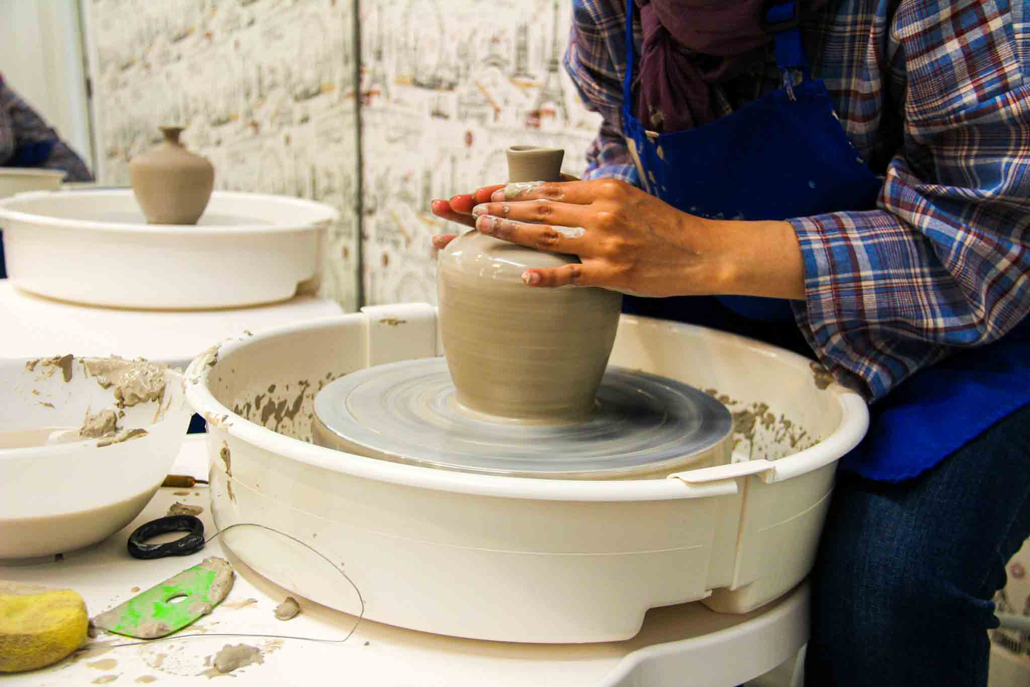 Participants practicing pottery making on wheels in a group session.